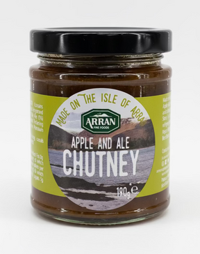 A 190g jar of Apple and Arran Ale Chutney from Arran Fine Foods features a green label adorned with a picturesque landscape and prominently states "Made on the Isle of Arran." This sweet chutney, capped with a black lid, offers a delightful blend of flavors.