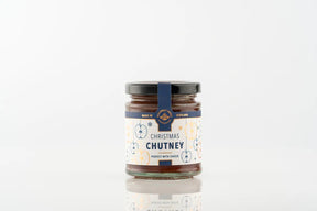 A small glass jar of Christmas Chutney, featuring a label with blue and gold illustrations of apples and stars.