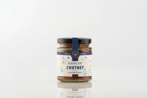 A glass jar of Boxing Day Chutney with a label featuring pear illustrations and text that reads “Boxing Day Chutney with pears & spices,” a savory sandwich spread.