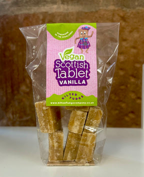 A clear bag of dairy-free Scottish Vegan Tablet from The Kilted Fudge Company, with a pink label featuring a cartoon kilted character and the product name "Scottish Vegan Tablet" in white and green text.
