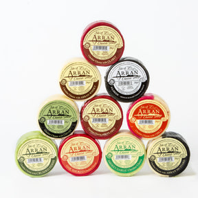 A stack of eight circular Arran Cheeses, each in colorful wax with unique labels and flavors, is displayed against a white background—perfect for the 8 x Arran Cheeses Deal.