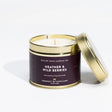An Isle of Skye Heather and Wild Berries Travel Tin Candle by Isle of Skye Candle Co. is displayed with its lid resting nearby. The white candle comes in a gold tin, featuring a label that describes it as a handmade natural soya wax candle from the Isle of Skye, infused with Scottish heather harvested in Scotland.