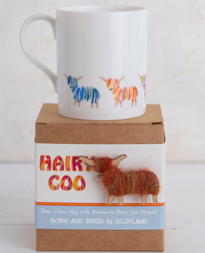 The Hairy Coo Mug, made of white Bone China and decorated with colorful Highland cows, comes in a gift box featuring a fuzzy handmade cow, the phrase “Born and bred in Scotland,” and includes a Hairy Coo magnet.