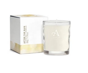 An 8cl After The Rain Candle with white wax is labeled "ARRAN" and sits beside its white and gold box that reads “After the Rain Scented Candle” in vertical text, promising a fresh, clean fragrance.