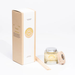 A brown box labeled "Lemongrass Reed Diffuser – Isle of Skye Candle Company" stands beside a glass jar with silver lid, wooden cap, and reed sticks. Both feature matching yellow and white branding. Made in Scotland.