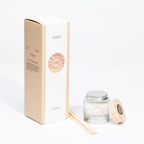 The Isle of Skye Candle Company’s Lily & Bergamot Reed Diffuser is shown with its beige box, silver lid, wooden lid, and several reed sticks—all set on a white background for a fresh, long-lasting scent.
