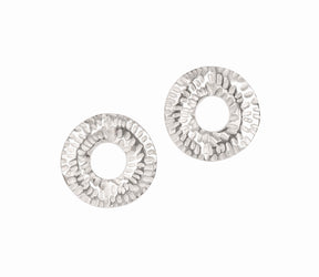 Caitlin Hegney Torus Mini Silver Studs are handcrafted Scottish earrings with silver, circular hammered textured surfaces and open centers, inspired by ancient artifacts and shown on a white background.