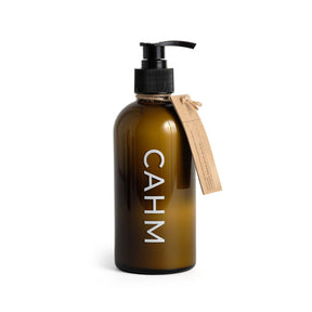 A refillable brown glass pump bottle labeled "CAHM" with a beige tag showcases the Atacama Hand & Body Lotion, a fragranced body lotion enriched with apricot kernel oil, set against a plain white background.