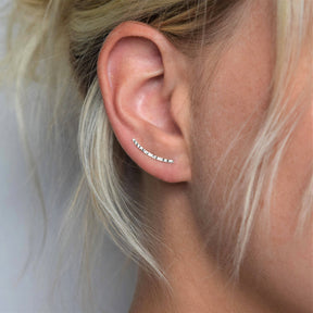 Close-up of a woman's ear with blonde hair, wearing the MUKA Textured Silver Ear Climber crafted from recycled sterling silver and featuring a delicate, sparkling design along the earlobe.