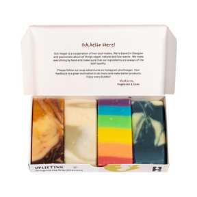 An open box presents the Uplifting Soap Gift Set, featuring four colorful bars of artisan soap in unique patterns. The inside lid offers a welcoming message along with details about Och Vegan, creating a thoughtful gift that highlights the finest in Scottish skincare.