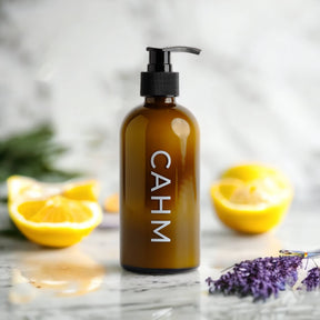 A brown CAHM pump bottle labeled "Amalfi Coast Hand Lotion" rests on marble among sliced lemons and lavender, offering a cruelty-free, sustainably luxurious scent inspired by the Amalfi Coast.