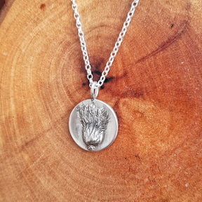 A Dun Fion Bracelet with an embossed botanical design rests on a wooden surface with natural grain, evoking the wild beauty of the Isle of Arran and making it a truly meaningful piece.