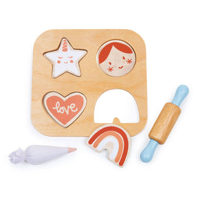 The Mentari Cookie Cutting Set includes a wooden puzzle with four cookie pieces—a unicorn star, girl’s face, heart labeled "love," and rainbow—plus a toy rolling pin and piping bag. Made from sustainable rubber wood.