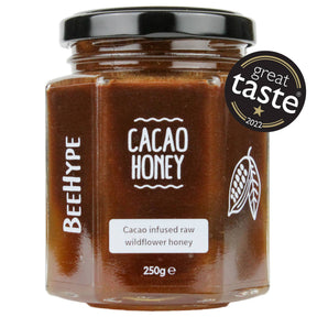A 250g hexagonal jar of BeeHype Cacao Honey, a cacao-infused raw wildflower honey and dairy-free chocolate spread, with a black lid and "Great Taste 2022" award badge.