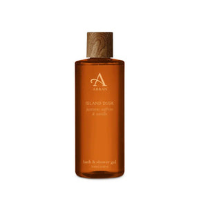 A clear amber bottle of Island Dusk Bath and Shower Gel 300ml with a brown wood-textured cap. The label highlights notes of jasmine, saffron, and vanilla.