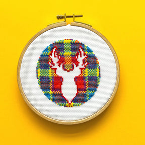 The Vivid Stash Cross Stitch Kit features a round hoop displaying a colorful cross-stitched stag head with antlers on patterned white fabric, set against a bold yellow background.