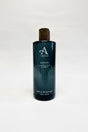 A 300ml (10.1 fl oz) dark green bottle of Sannox Bath and Shower Gel, offering an invigorating "Leather, Oud & Amber" scent. This men's fragrance, complete with a wooden cap, is ideal for a luxurious bathing experience.